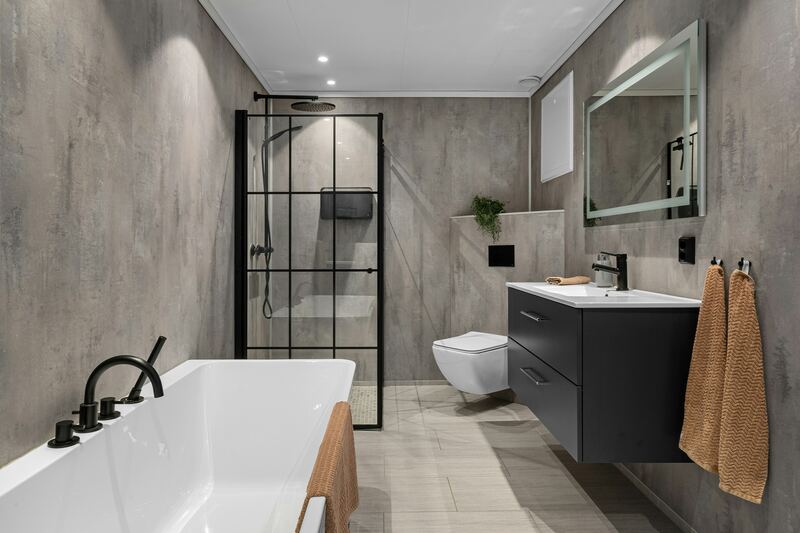 Afgewerkte badkamer met grote grijze tegels, een bad, een hangtoilet en een wastafel.