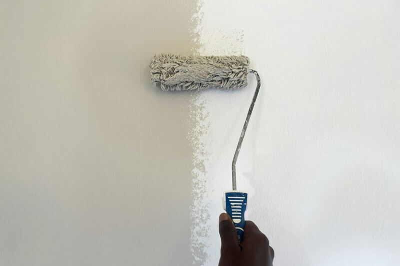 Verfroller die een witte laag op een muur aanbrengt.